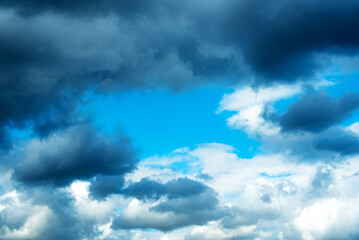 Naklejka na ściany i meble Blue sky with a frame of dark clouds and white clouds