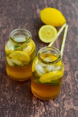 Iced tea in jars with lemon slices and mint leaves on rustic background