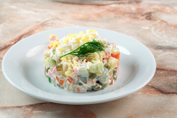 Russian cuisine-Olivier salad with boiled vegetables, eggs and meat. The salad is served on a plate in the form of a circle