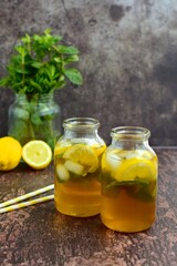 Iced tea with lemon slices and mint leaves on rustic background