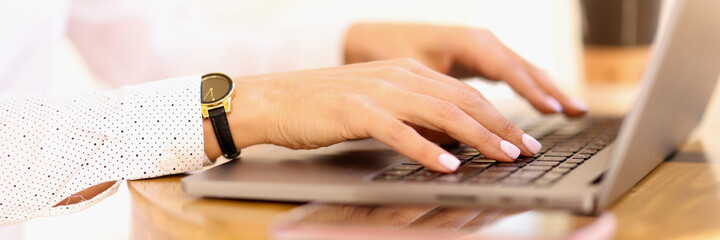 Female hands are typing on laptop keyboard closeup. Remote work online concept.