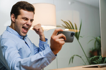 Happy young businessman using smartphone