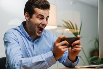 Happy young businessman using smartphone