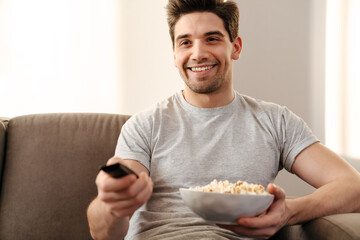Happy man watching tv and eating popcorn
