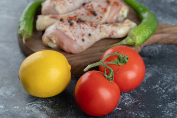 Close up photo of Fresh organic tomatoes and lemon with raw chicken legs