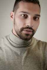 Obraz premium Portrait of a young brown-haired man with a short beard and a gray turtleneck sweater