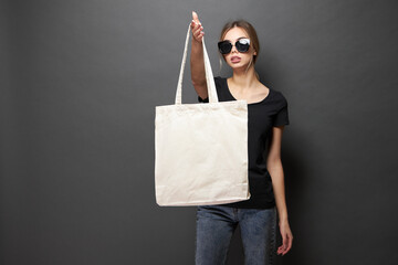 Tote eco bag for mockup is held by a woman over gray texture