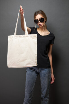 Tote eco bag for mockup is held by a woman over gray texture