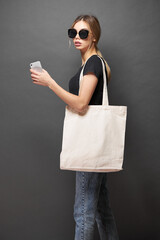 Tote eco bag for mockup is held by a woman over gray texture