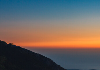 beautiful sunset above the hills with lights from cafe  with view over sea