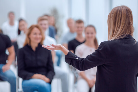 rear view. young woman doing a report for a group of young people
