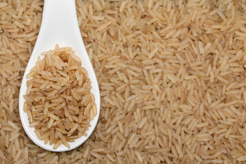 Natural brown whole grain rice in a white spoon