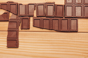 broken bar of chocolate on wooden background top view texture sweets candy