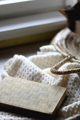 Vintage book, woven basket, tabby cat and crochet blanket. Cozy details at home. Selective focus.