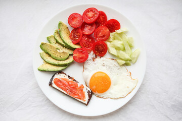 Breakfast on a ketogenic diet, healthy eating program- eggs, cucumbers, cherry tomato, rye bread with salmon and avocado