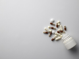 Various forms of tablets, capsules and medicines scattered from the bottle on a light background. Pharmacy, people and health concept. Drug prescription for treatment medication. Top view, mock up.