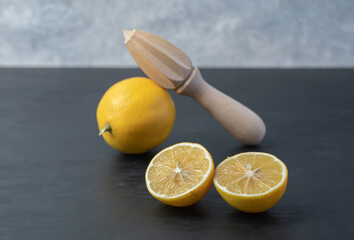 Fresh yellow sliced and whole lemons with a wooden reamer