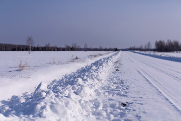 Fototapeta na wymiar Winter road leading through a snowfield