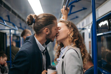 man and a woman in love kiss on a subway train.