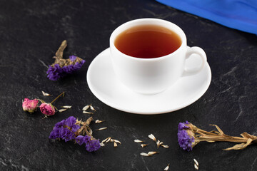 A cup of tea with dried flowers on a black background