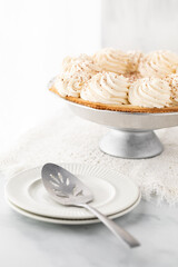 Close up of a banana cream pie with plates and a spatula in front ready for serving.