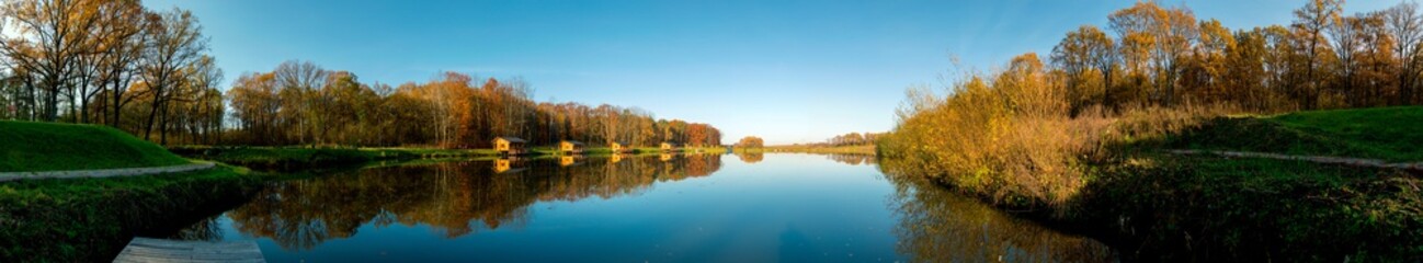 Fototapeta premium Forest lake with reflection under high mountains on a sunny spring day