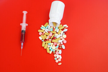 Pile of medical capsules pills in red and white color on red background, top view for copy space