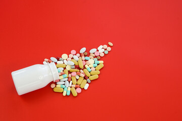 Pile of medical capsules pills in red and white color on red background, top view for copy space