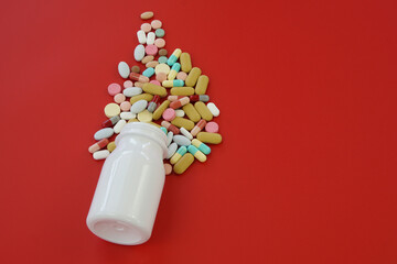 Pile of medical capsules pills in red and white color on red background, top view for copy space