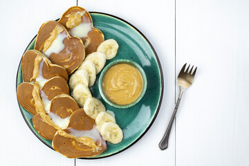 Heart-shaped pancakes topped with condensed milk and peanut butter with bananas