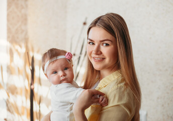 Beautiful young mother with a baby girl in her arms. A look at the camera