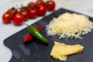 Grated Parmesan cheese on black stone with garlic, onion, pepper and other spices