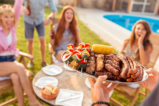 Friends having a backyard barbecue party - Powered by Adobe