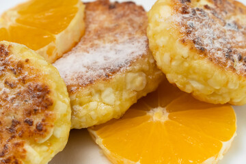 Close-up of cottage cheese pancake sprinkled with powdered sugar with orange circles. Beautiful background of a delicious, healthy breakfast