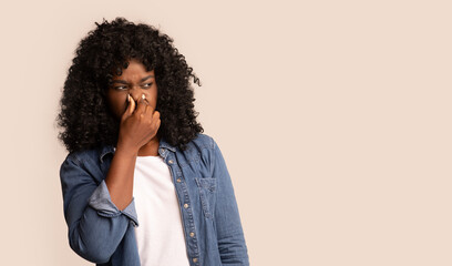 Black woman closing nose with fingers, feeling unpleasant scent