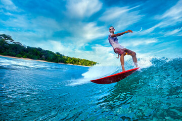 Male surfer on a blue wave at sunny day