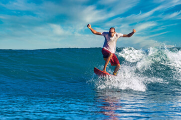 Male surfer on a blue wave at sunny day