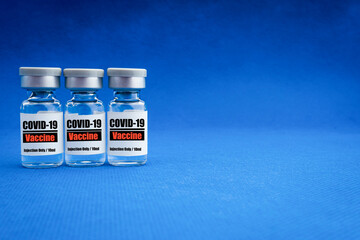 COVID-19 VACCINE text with vial on blue background. Covid-19 or Coronavirus Concept