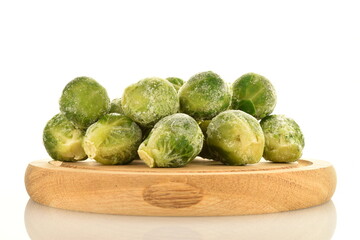 Several frozen natural brussels sprouts on a wooden tray, close-up, isolated on white.