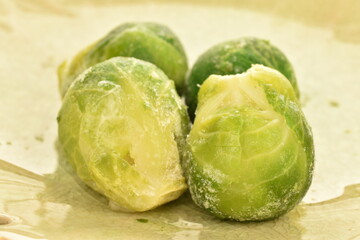 Several frozen organic Brussels sprouts in a ceramic bowl, close-up.