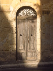 Stare szare drewniane drzwi w cieniu na Malcie - obrazy, fototapety, plakaty