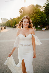 Fototapeta na wymiar solar glare. bride with long curls in a white elegant dress
