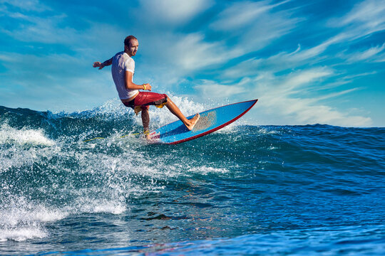 Male surfer on a blue wave at sunny day
