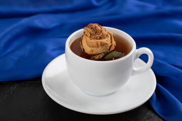 Dried rose in a cup of hot tea on a black background