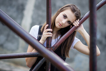 Obraz premium Portrait of a brunette girl outdoors, leaning on the metal fence