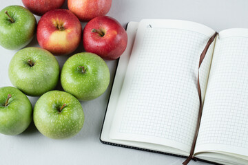 Green and red apples with a blank cookbook aside