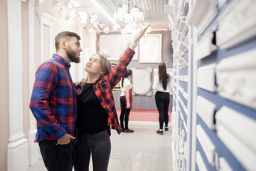 Young couple choosing skirting boards for ceiling and floor in flooring store