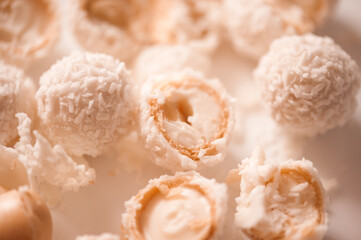 Cracked candy with almond and coconut flakes on white table closeup. Sweet tasty pastry. Top view.