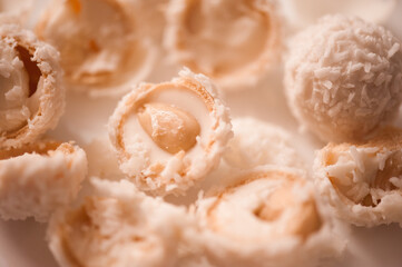 Cracked candy with almond and coconut flakes on white table closeup. Sweet tasty pastry. Top view.