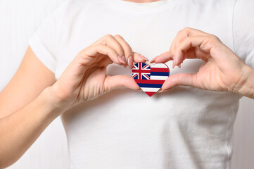 Love Hawaii. The girl holds a heart in the form of the flag of Hawaii on her chest. Hawaiian patriotism concept